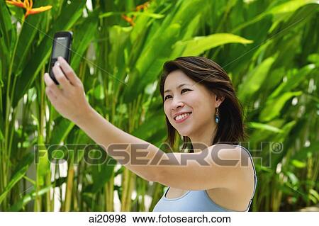Woman outdoors, using mobile phone to take a picture of herself View Large Photo Image Stock Photo - Woman outdoors, using mobile phone to take a picture of herself. Fotosearch