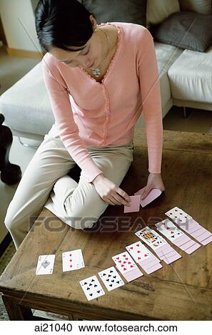 Stock Image - Woman sitting on table, dealing cards. Fotosearch