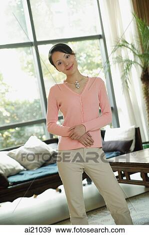 Woman standing in living room looking at camera View Large Photo Image Stock Photo - Woman standing in living room looking at camera. Fotosearch