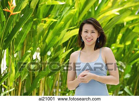 Stock Image - Woman standing outdoors, smiling at camera. Fotosearch