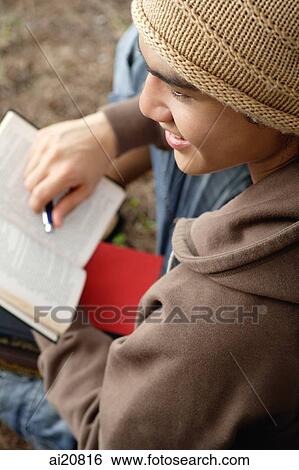 Young man holding book, high angle view View Large Photo Image Stock Photograph - Young man holding book, high angle view. Fotosearch