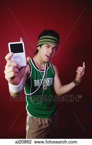 Young man holding MP3 player towards camera View Large Photo Image Stock Image - Young man holding MP3 player towards camera. Fotosearch
