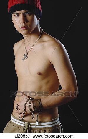 Stock Photo - Young man in studio wearing cap and cross necklace. Fotosearch