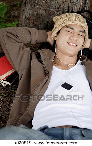 Young man listening to MP3 player, eyes closed View Large Photo Image Stock Photo - Young man listening to MP3 player, eyes closed. Fotosearch