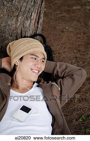 Young man listening to MP3 player, smiling View Large Photo Image Stock Image - Young man listening to MP3 player, smiling. Fotosearch