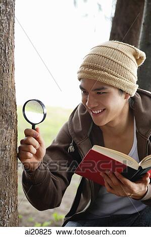 Young man with book and magnifying glass, looking at tree trunk View Large Photo Image Stock Photography - Young man with book and magnifying glass, looking at tree trunk. Fotosearch