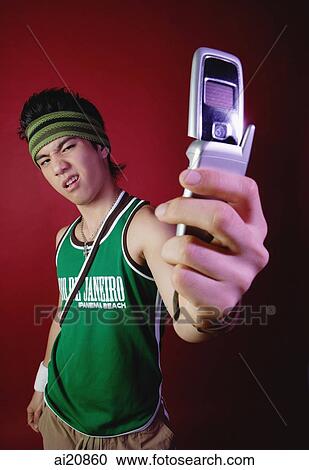 Stock Image - Young man with sweat band, holding mobile phone. Fotosearch