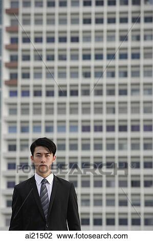 Businessman looking at camera, building behind him View Large Photo Image Stock Image - Businessman looking at camera, building behind him. Fotosearch
