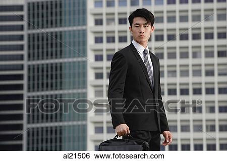 Businessman looking at camera, holding briefcase View Large Photo Image Stock Photograph - Businessman looking at camera, holding briefcase. Fotosearch