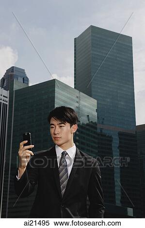 Businessman looking at mobile phone, cityscape in the background View Large Photo Image Stock Photography - Businessman looking at mobile phone, cityscape in the background. Fotosearch