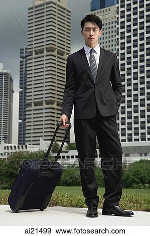 Businessman pulling luggage, looking at camera View Large Photo Image Stock Photo - Businessman pulling luggage, looking at camera. Fotosearch