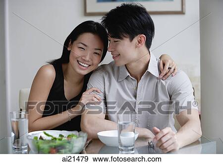 Couple at home, sitting by dining table, woman looking at camera View Large Photo Image Stock Photo - Couple at home, sitting by dining table, woman looking at camera. Fotosearch