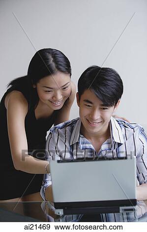 Couple looking at laptop View Large Photo Image Stock Photo - Couple looking at laptop. Fotosearch