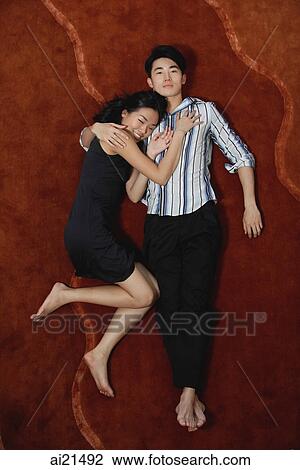 Stock Image - Couple lying on floor, high angle view. Fotosearch