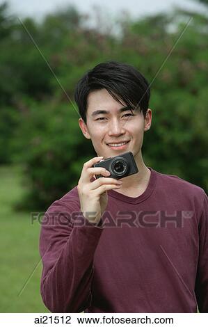 Man holding camera, smiling View Large Photo Image Stock Image - Man holding camera, smiling. Fotosearch