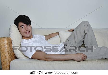 Man lying on sofa View Large Photo Image Picture - Man lying on sofa. Fotosearch