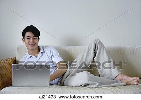 Man lying on sofa with laptop View Large Photo Image Stock Image - Man lying on sofa with laptop. Fotosearch