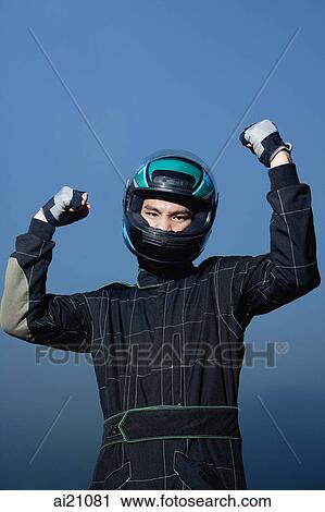 Stock Image - Race car driver in protective sportswear, raising fists. Fotosearch