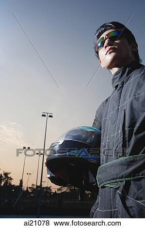 Racing driver, holding helmet, low angle view View Large Photo Image Stock Photo - Racing driver, holding helmet, low angle view. Fotosearch