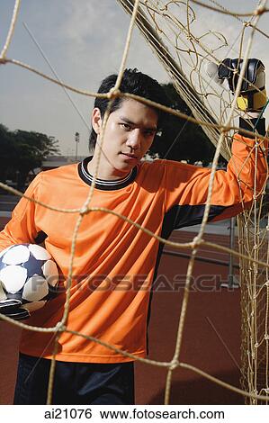 Soccer goalie holding soccer ball, leaning on goal post net View Large Photo Image Stock Photograph - Soccer goalie holding soccer ball, leaning on goal post net. Fotosearch