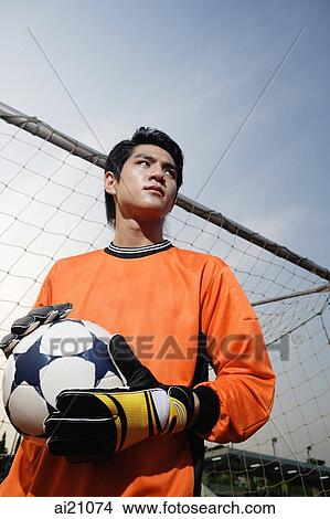 Soccer goalie standing next to goal post, holding soccer ball View Large Photo Image Picture - Soccer goalie standing next to goal post, holding soccer ball. Fotosearch