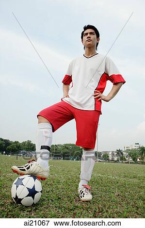 Soccer player standing with one foot on ball and hands on hips View Large Photo Image Stock Photo - Soccer player standing with one foot on ball and hands on hips. Fotosearch