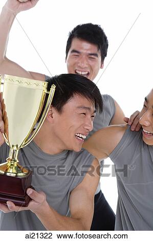 Stock Image - Three people celebrating with trophy. Fotosearch
