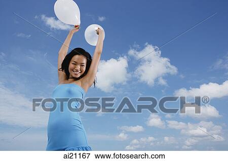 Woman holding balloons in air View Large Photo Image Stock Photo - Woman holding balloons in air. Fotosearch