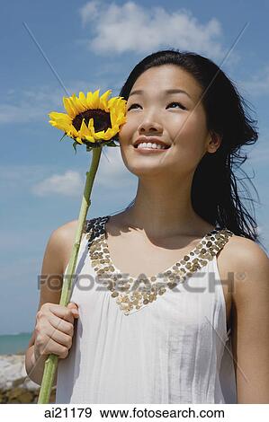 Woman holding sunflower stalk, looking up View Large Photo Image Stock Photo - Woman holding sunflower stalk, looking up. Fotosearch