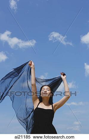Woman in black dress, eyes closed, holding scarf in air View Large Photo Image Stock Photography - Woman in black dress, eyes closed, holding scarf in air. Fotosearch