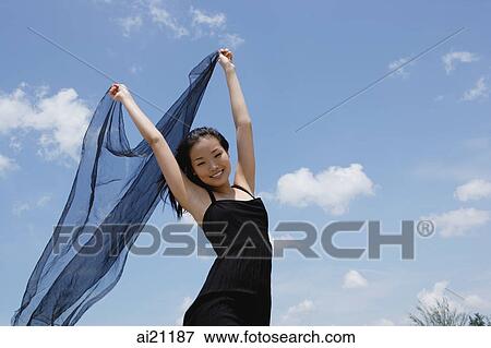 Woman in black dress, holding scarf in air View Large Photo Image Stock Photo - Woman in black dress, holding scarf in air. Fotosearch