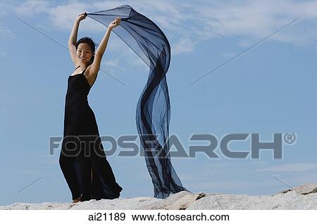 Woman in long black dress, holding scarf in air View Large Photo Image Stock Photo - Woman in long black dress, holding scarf in air. Fotosearch