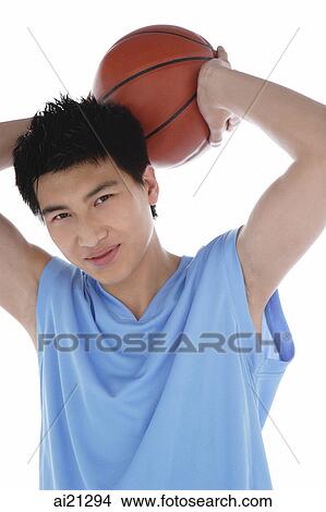 Young man holding basketball behind his head, smiling View Large Photo Image Picture - Young man holding basketball behind his head, smiling. Fotosearch