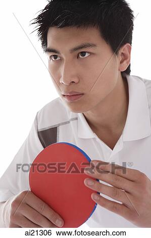 Young man holding table tennis paddle, looking away View Large Photo Image Stock Photograph - Young man holding table tennis paddle, looking away. Fotosearch