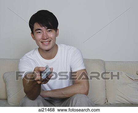 Young man holding TV remote control, smiling View Large Photo Image Stock Photo - Young man holding TV remote control, smiling. Fotosearch