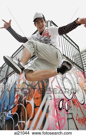 Young man jumping in mid-air, looking at camera View Large Photo Image Picture - Young man jumping in mid-air, looking at camera. Fotosearch