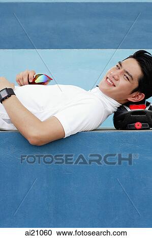 Young man lying on cycling helmet, smiling at camera View Large Photo Image Stock Image - Young man lying on cycling helmet, smiling at camera. Fotosearch