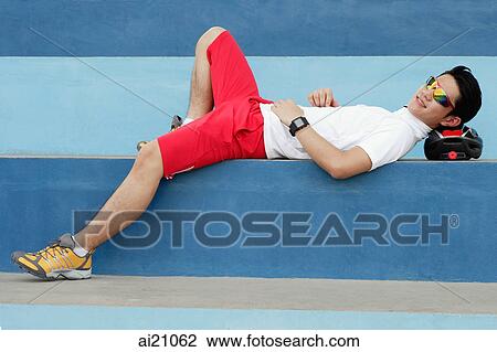 Stock Image - Young man lying on cycling helmet, resting. Fotosearch