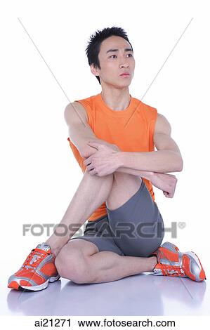 Young man sitting on floor, legs and arms crossed View Large Photo Image Stock Image - Young man sitting on floor, legs and arms crossed. Fotosearch