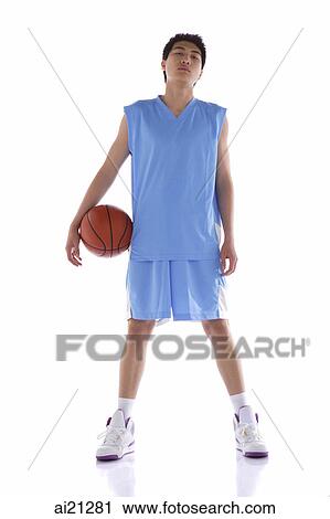 Stock Image - Young man standing with basketball. Fotosearch