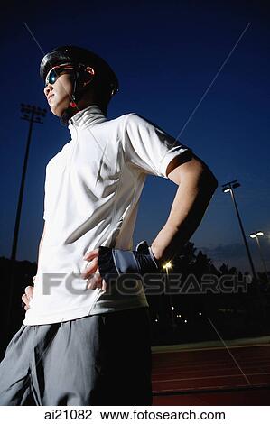 Young man wearing cycling helmet and sunglasses, hands on hips, looking away View Large Photo Image Stock Image - Young man wearing cycling helmet and sunglasses, hands on hips, looking away. Fotosearch