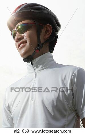 Young man wearing cycling helmet and sunglasses, looking away View Large Photo Image Stock Photo - Young man wearing cycling helmet and sunglasses, looking away. Fotosearch