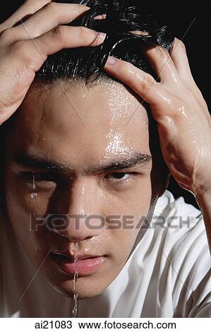 Stock Image - Young man with hands in hair, face wet with water. Fotosearch
