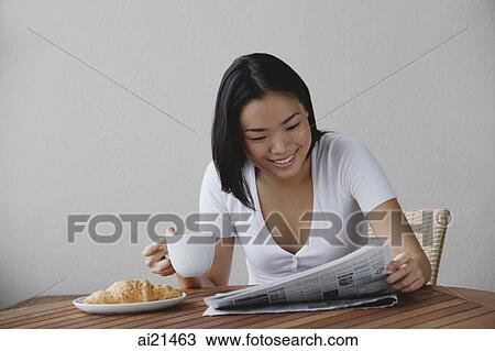 Young woman having breakfast and reading newspaper View Large Photo Image Stock Image - Young woman having breakfast and reading newspaper. Fotosearch