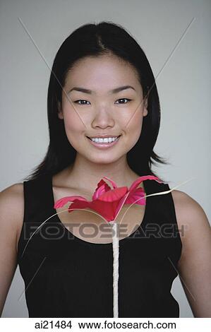 Young woman holding flower, head shot View Large Photo Image Picture - Young woman holding flower, head shot. Fotosearch
