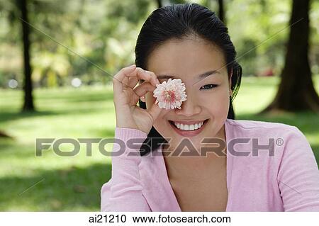 Young woman holding flower over eye View Large Photo Image Stock Image - Young woman holding flower over eye. Fotosearch