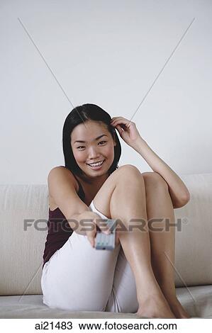 Young woman holding TV remote control, smiling View Large Photo Image Stock Image - Young woman holding TV remote control, smiling. Fotosearch