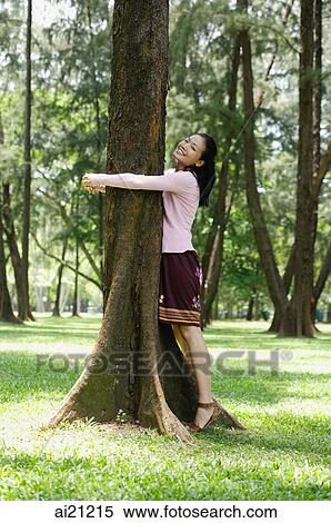 Young woman hugging a tree, smiling View Large Photo Image Stock Photography - Young woman hugging a tree, smiling. Fotosearch