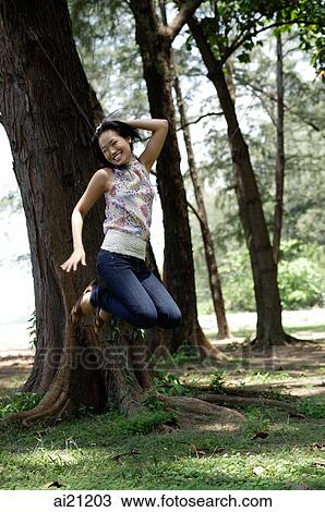 Young woman in park, jumping View Large Photo Image Stock Image - Young woman in park, jumping. Fotosearch