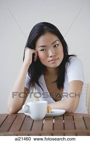 Young woman leaning head on hand, cup and saucer on table View Large Photo Image Stock Image - Young woman leaning head on hand, cup and saucer on table. Fotosearch